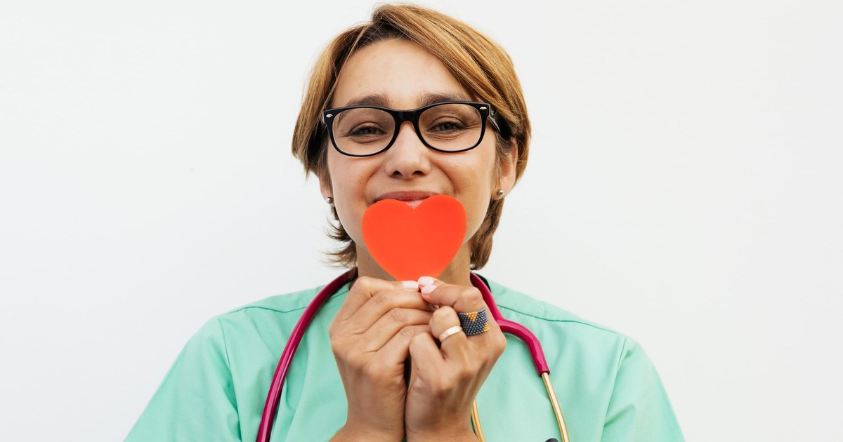 Doctor holding a red heart symbol, promoting healthcare compassion.