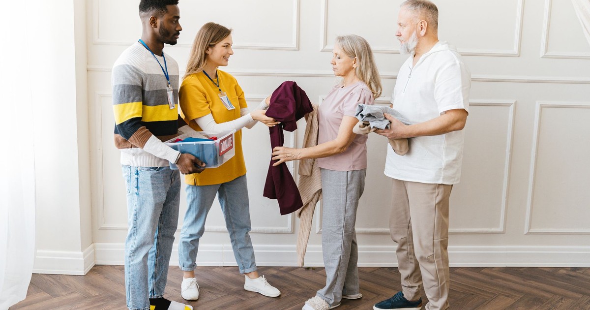Diverse volunteers distributing clothes indoors, showcasing kindness and community support.