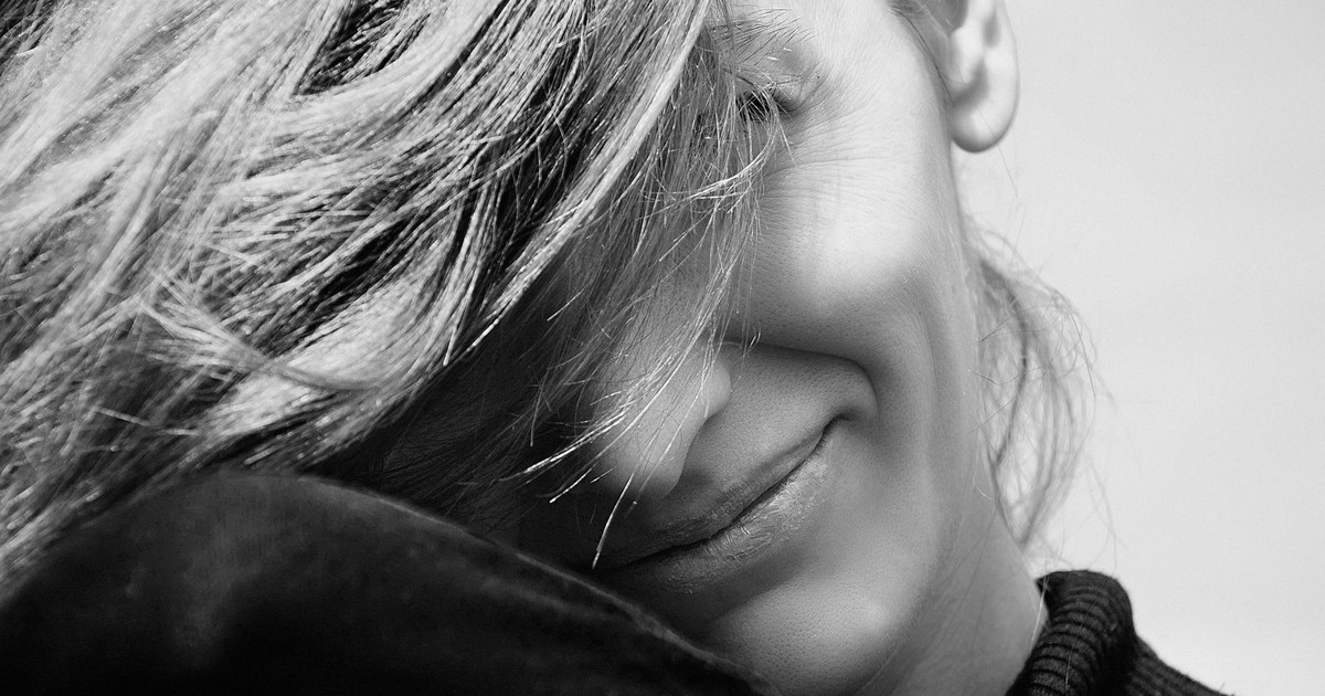 Captivating black and white close-up portrait of a smiling woman with long hair.