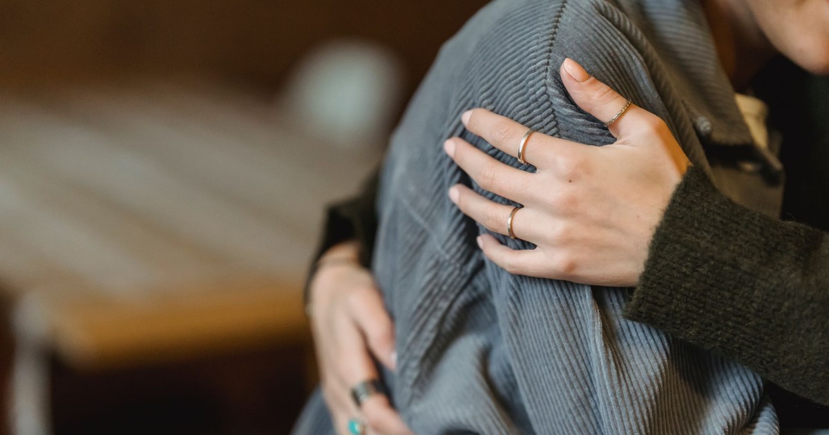 High angle of crop anonymous delicate female cuddling crying girlfriend suffering from misfortune and grief