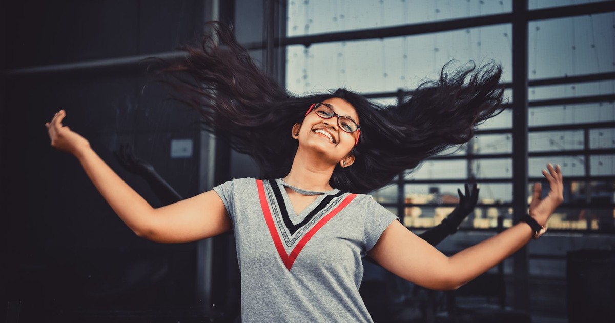 Smiling Indian woman with flowing hair outdoors in Hyderabad, expressing joy and freedom.