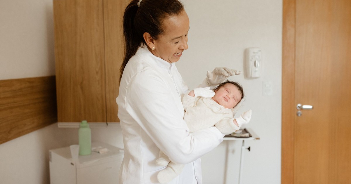 A medical practitioner gently holding a newborn baby in a hospital room, symbolizing care and health.
