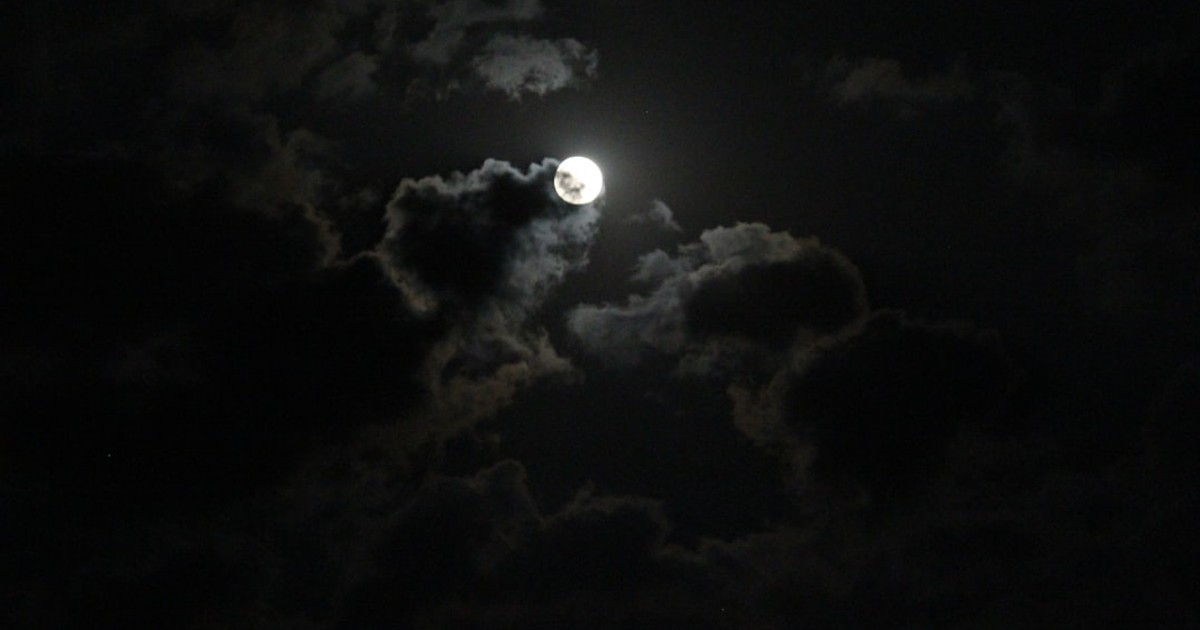 a full moon is seen through the clouds