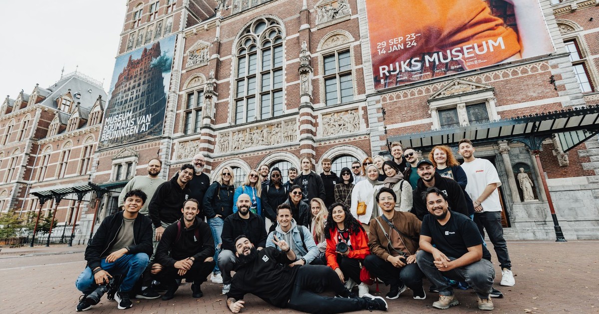 A cheerful group of friends posing in front of the iconic Rijksmuseum in Amsterdam.