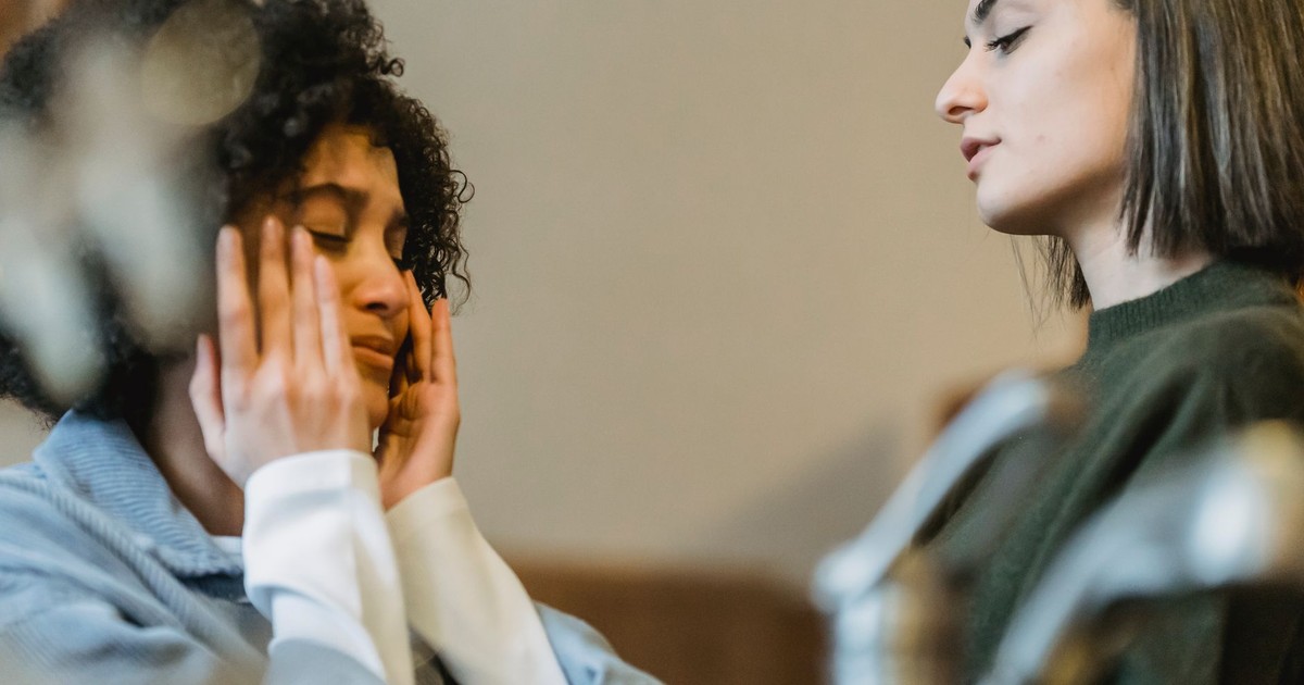 Low angle side view of upset African American crying and wiping away tears near crop girlfriend