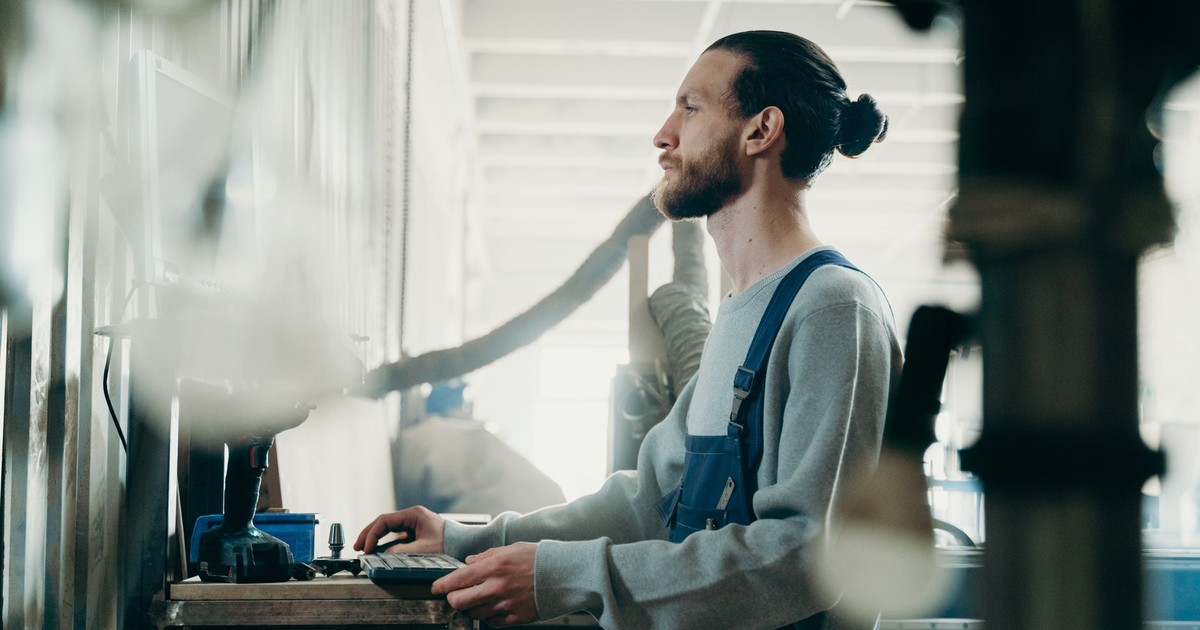 Bearded man with bun focused on his work at a modern industrial workspace.
