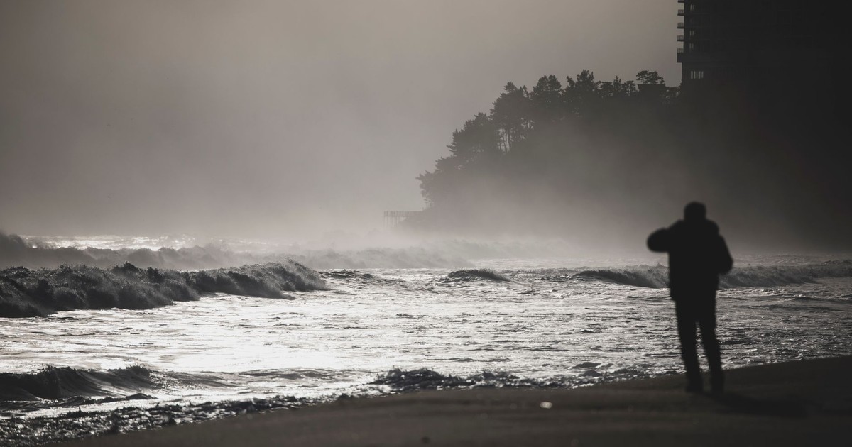 Silhouette of a person on a misty beach at Sokcho-si, South Korea, capturing the dramatic waves.