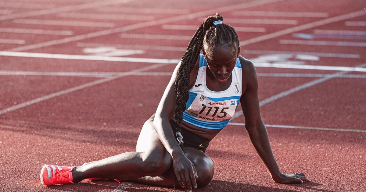 A female athlete in sports gear taking a break on the running track after a race, during daylight.