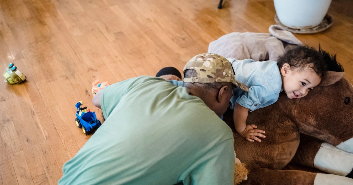 A joyful moment between a father and child playing with toys indoors.