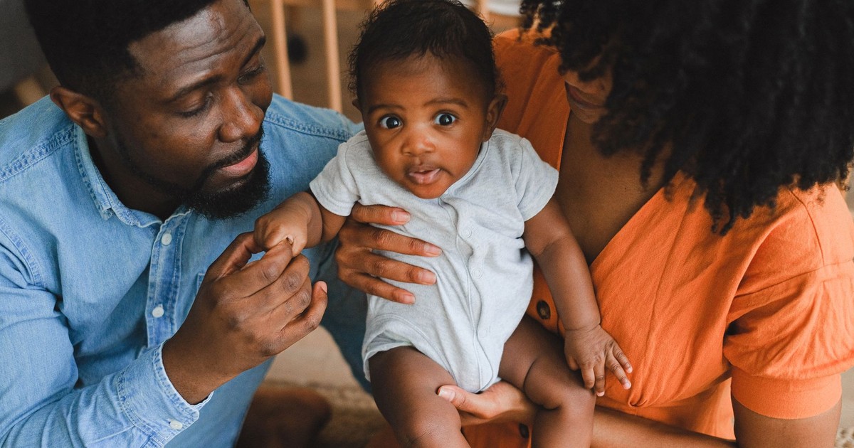 Loving parents holding adorable baby in a warm, intimate home environment.