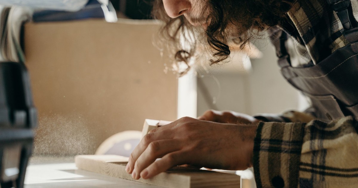 A dedicated craftsman skillfully sanding a wooden board in a cozy workshop setting.