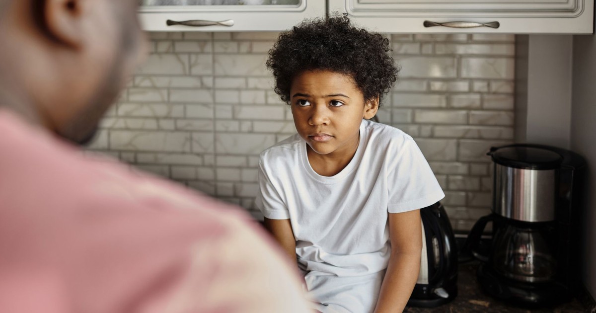 A father and son having an emotional conversation in a cozy kitchen setting.