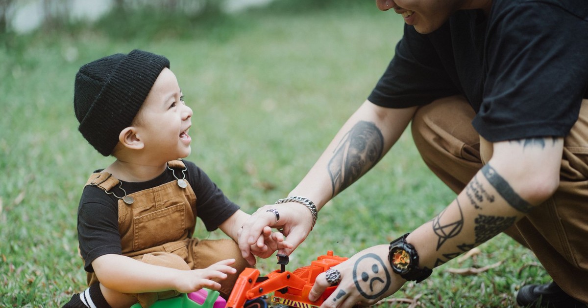 A joyful moment of a father and son playing with toys on the grass, capturing the essence of happy childhood.