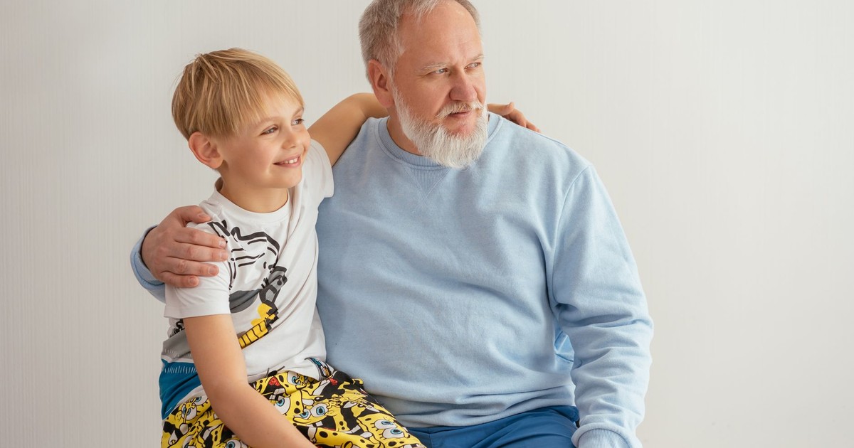 A grandfather and grandson sitting together, smiling and sharing a joyful moment.