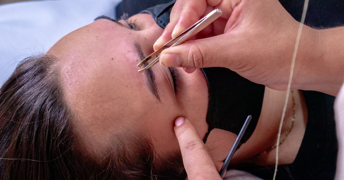 Close-up of a woman receiving an eyebrow tweezing treatment at a spa, enhancing facial beauty care.