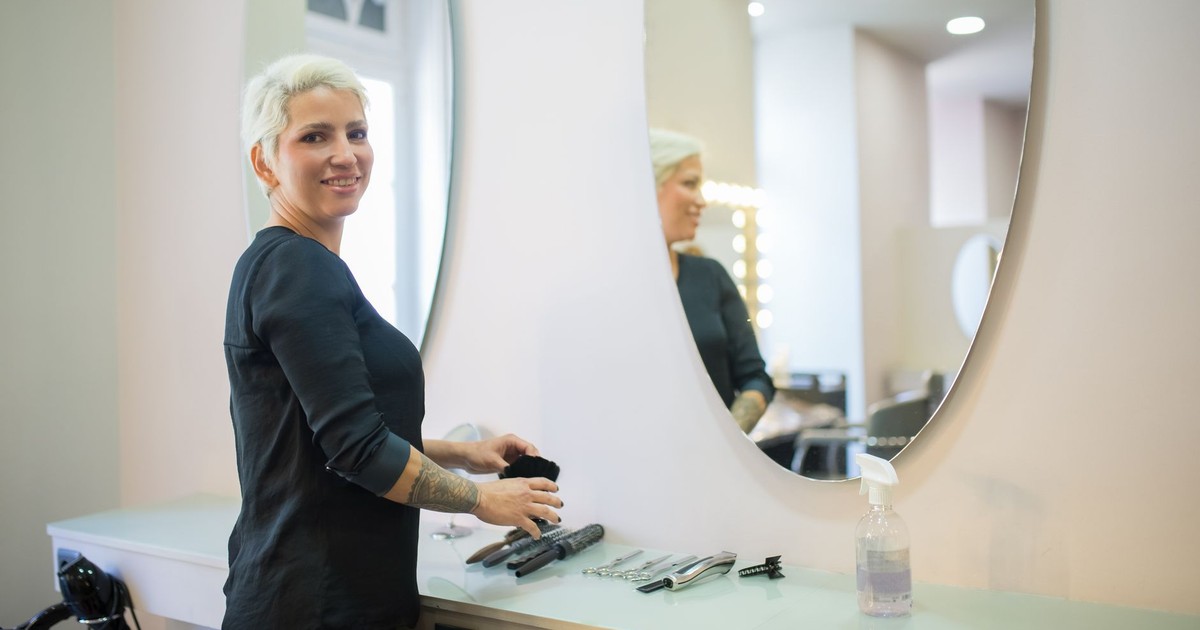 A hair stylist in a modern salon in Portugal with tools and a mirror.