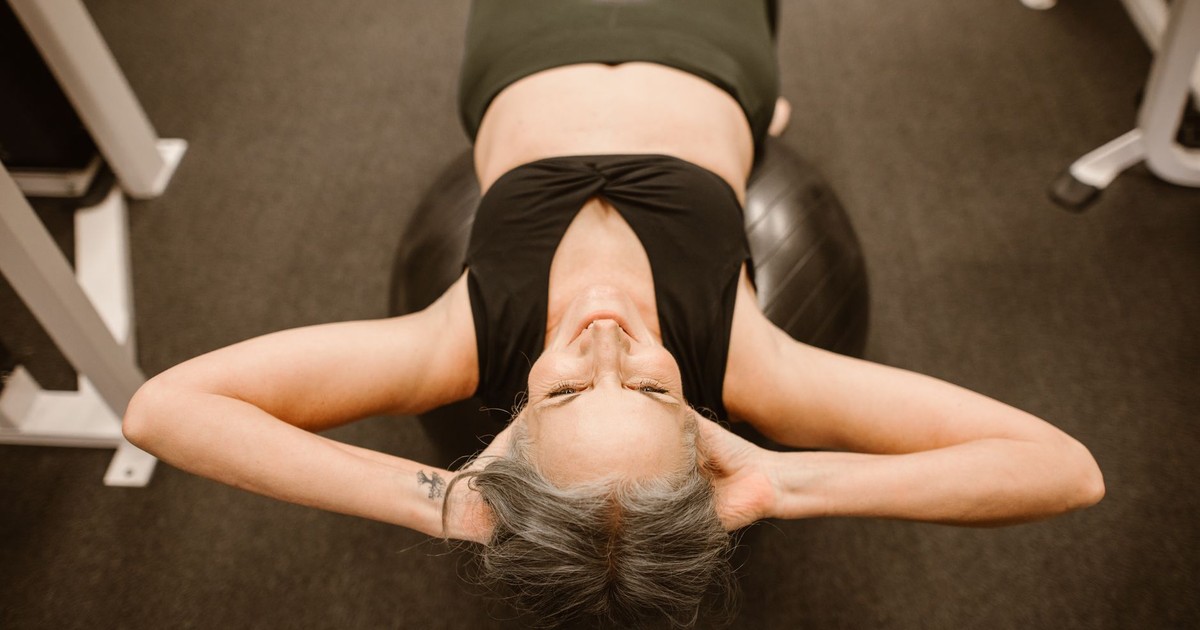 Senior woman performing exercise on stability ball for fitness and strength.