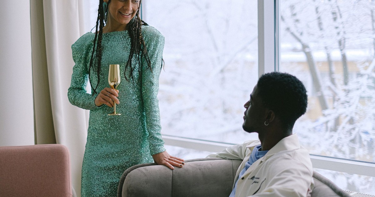 Stylish couple celebrating indoors with drinks by a frosty window.