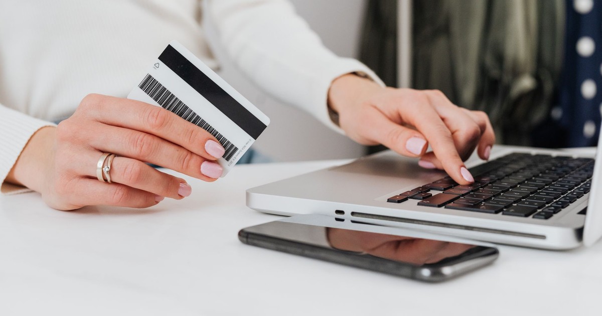 Close-up of a woman using a credit card for an online transaction on a laptop.