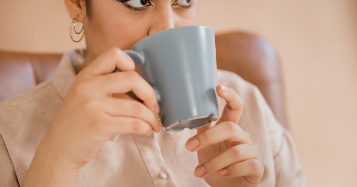 Woman enjoying a hot drink from a mug, illustrating comfort and relaxation.