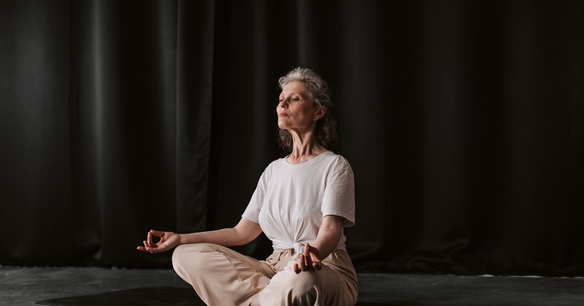 Senior woman practicing yoga in seated position indoors, focusing on mindfulness.
