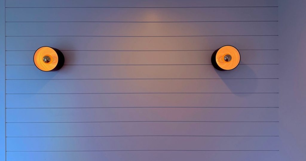 Stylish modern interior with two wall sconces illuminating a paneled wall.