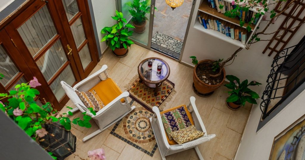 Inviting indoor patio with chairs, table, and lush plants creating a cozy retreat.