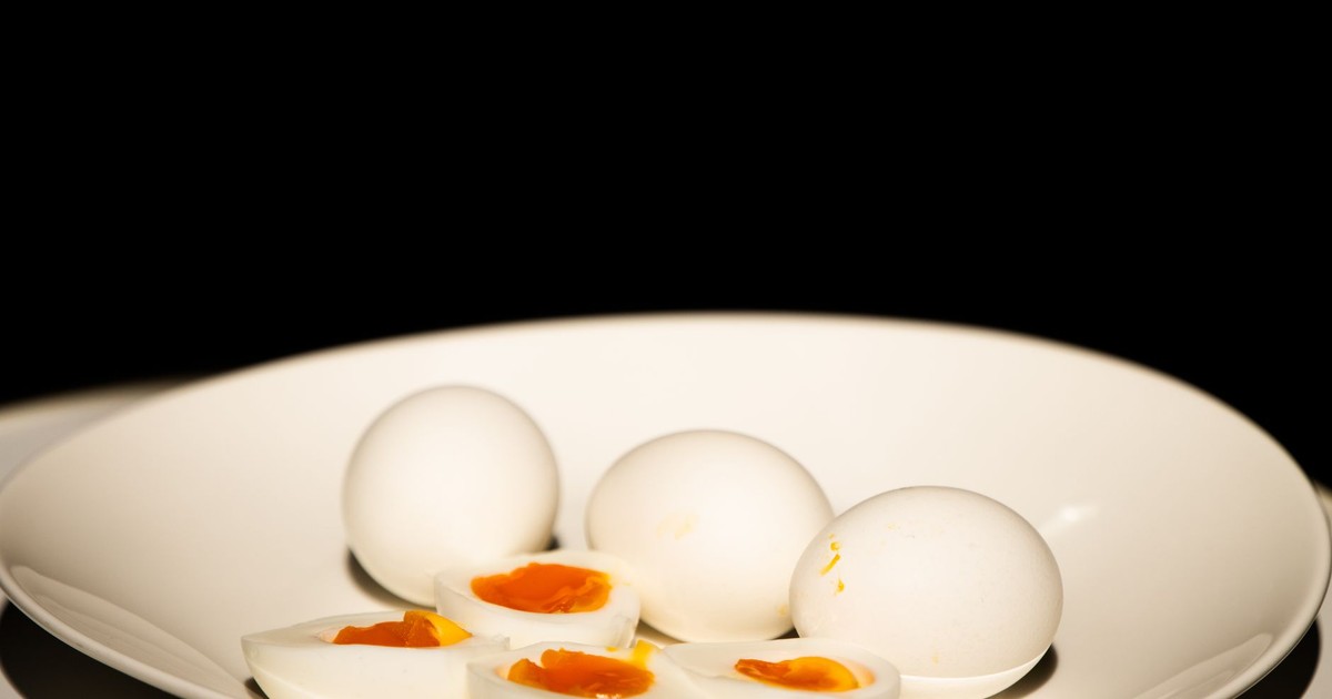A white plate of hard-boiled eggs, some sliced, against a dark background.