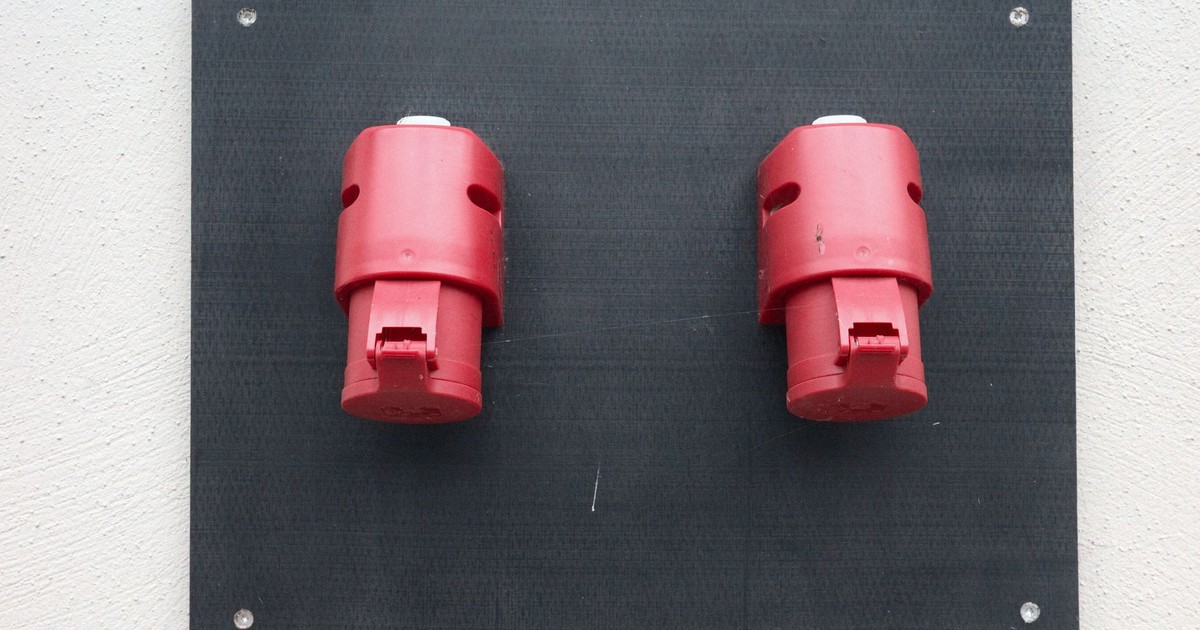Image of two red industrial electrical connectors mounted on a wall.