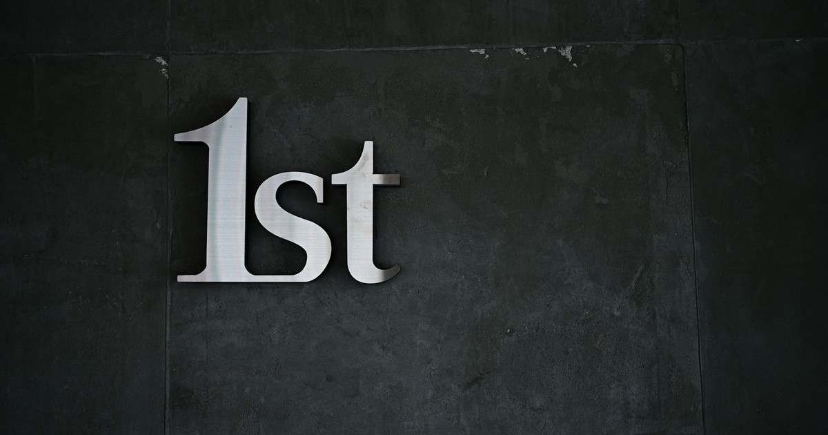 A close-up of '1st' metal lettering on a textured dark wall, offering a minimalist design.