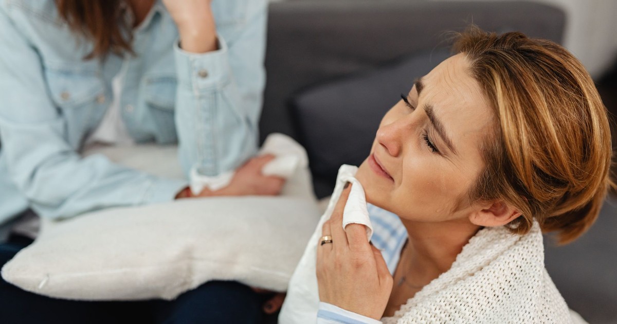 A woman crying with a napkin, comforted by a friend, expressing emotions.