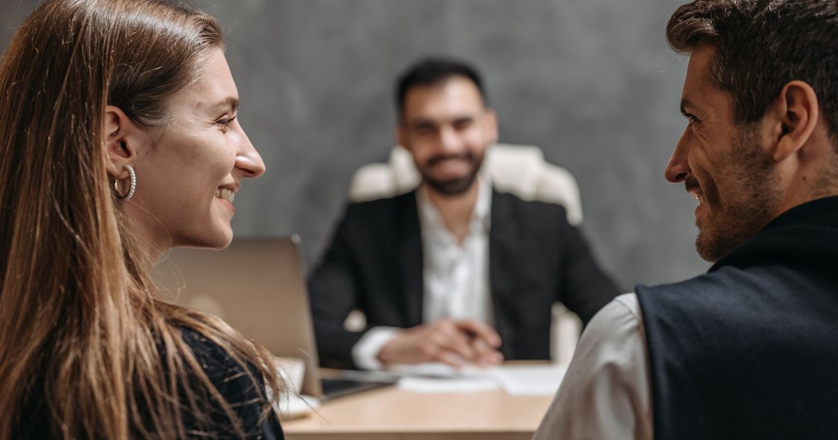 A friendly business meeting with smiling professionals seated in an office setting.
