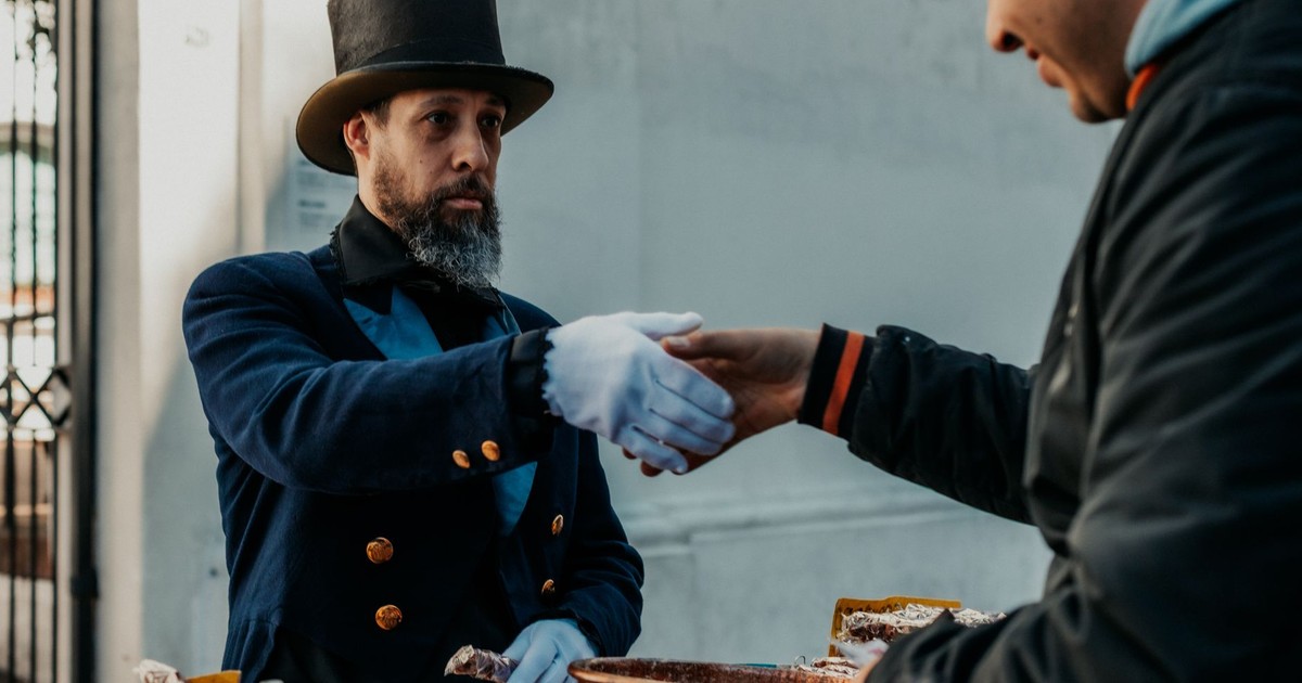 A street vendor in traditional attire interacts with a customer in Buenos Aires.