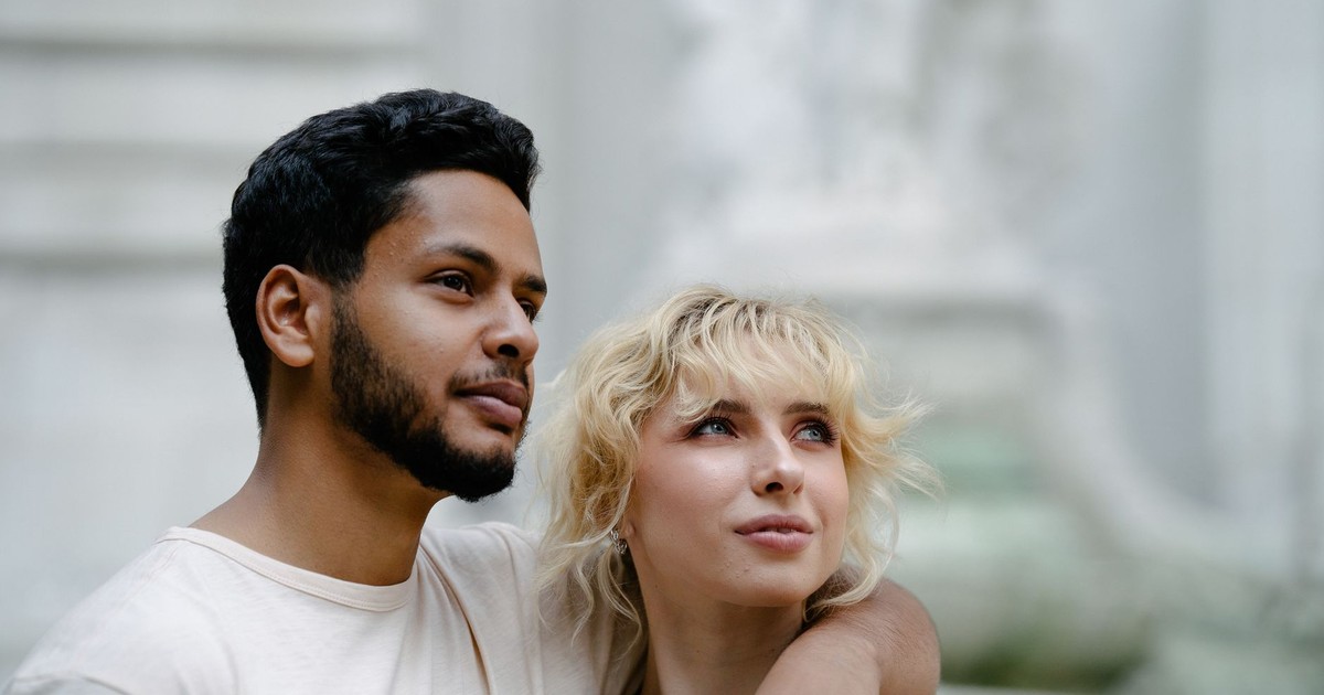 Close-up portrait of a loving interracial couple with arms around each other outdoors.