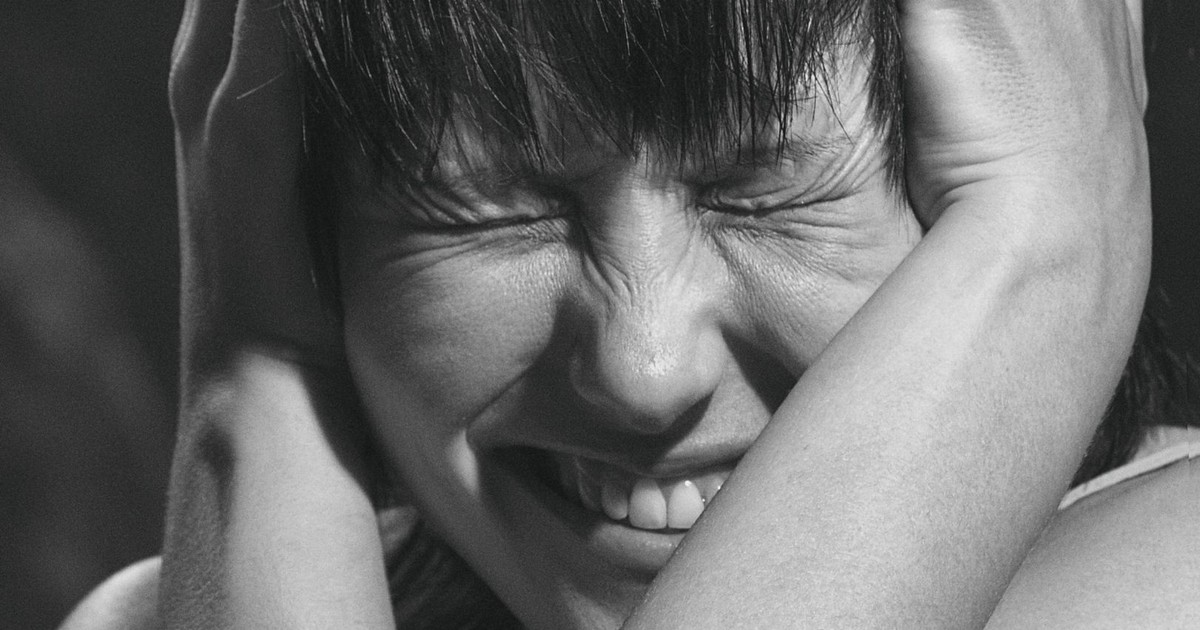 Emotional black and white close-up portrait of a woman expressing pain and frustration.