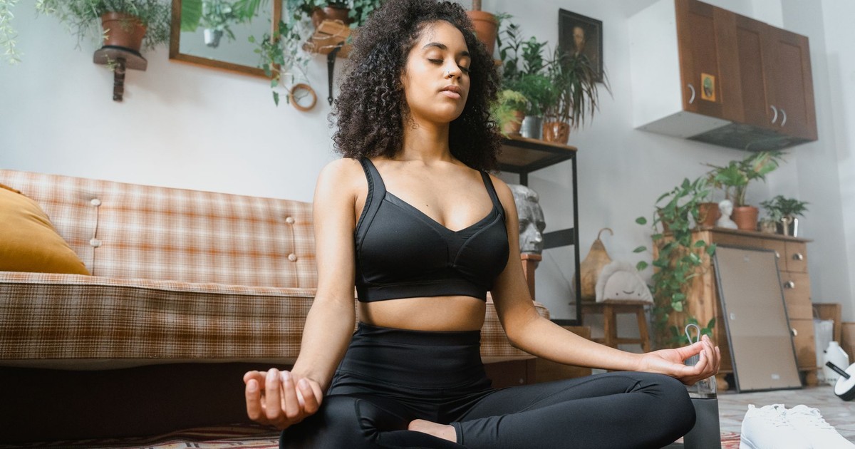 Calm woman in activewear meditating indoors, promoting a healthy lifestyle.