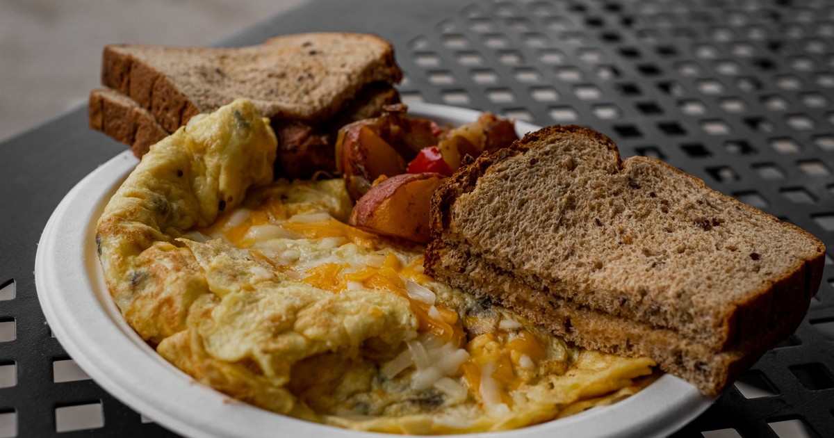 Delicious breakfast featuring an omelette, toast, and roasted potatoes on a white plate.