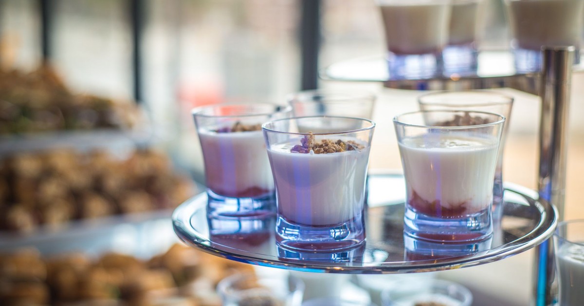 Yogurt parfaits elegantly displayed in glasses on a multi-tiered tray at a catering event.