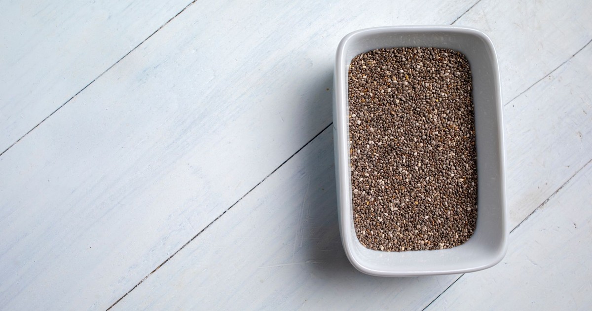 A close-up of chia seeds in a white bowl on a light wooden surface, showcasing a healthy food concept.