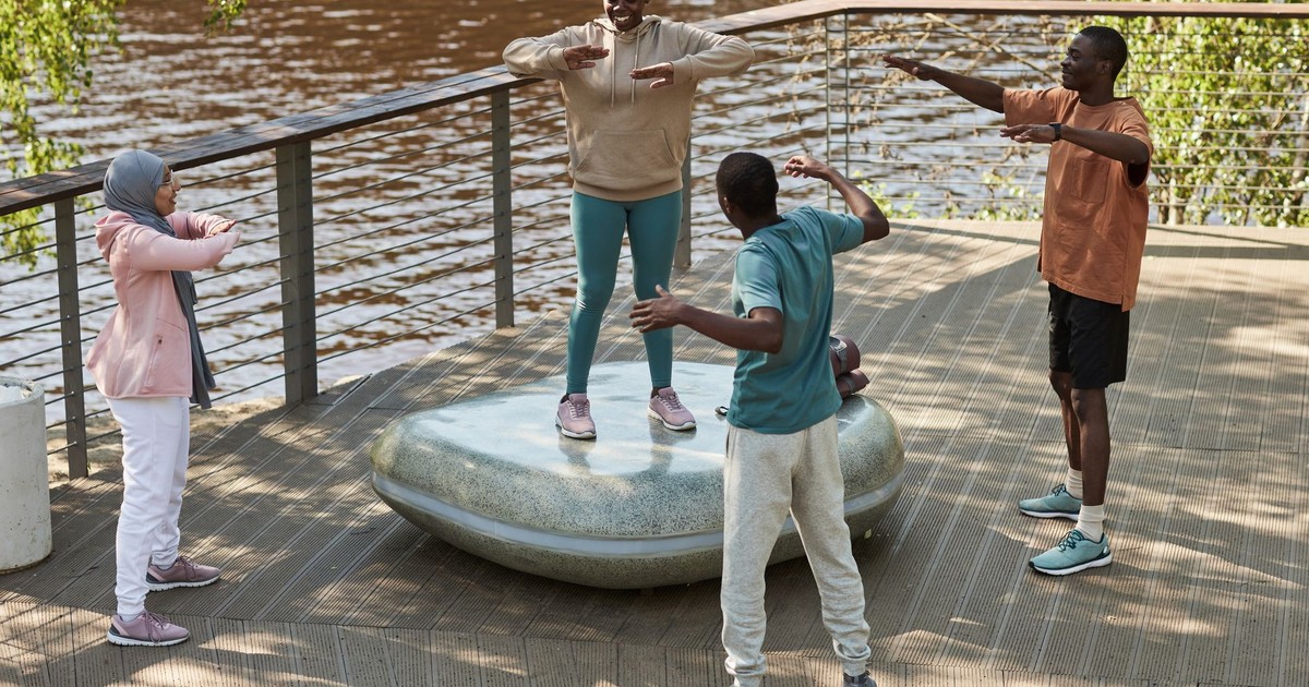 Friends enjoying an outdoor workout on a waterside deck, promoting health and togetherness.