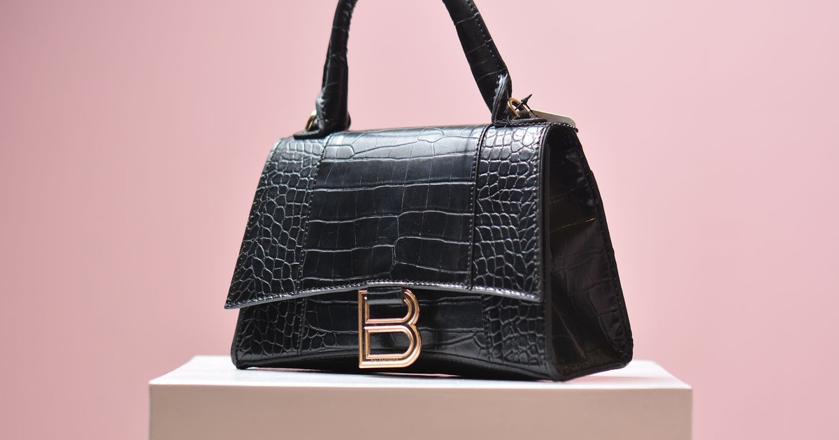 Elegant black leather handbag with textured design on a pink background, perfect for high-end fashion shoots.