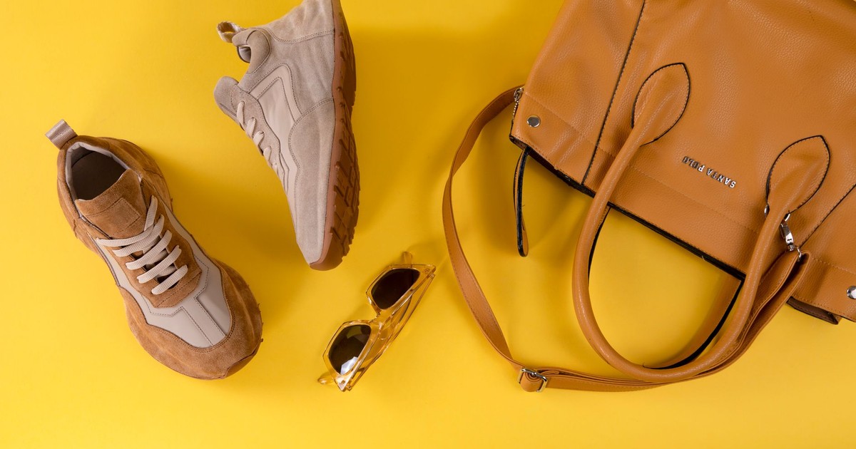Stylish brown handbag, fashionable eyewear, and sport shoes on vibrant yellow background.