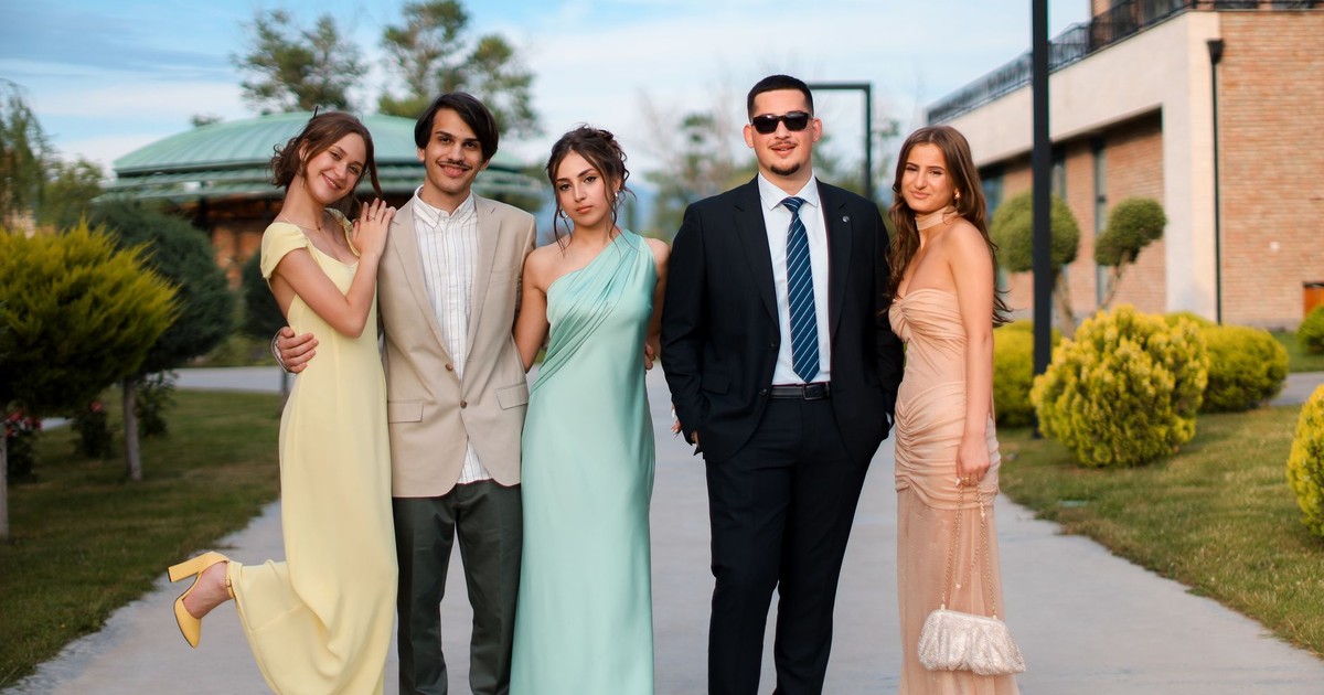 Group of young adults posing in stylish formal wear outdoors, exuding elegance and sophistication.