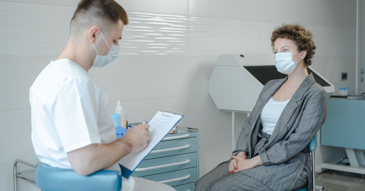 A doctor in a face mask consults a patient in a clinic, reflecting the new normal.