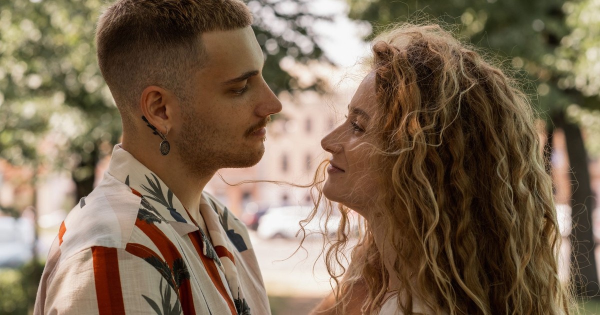 A couple lovingly gazing into each other's eyes in a sunny park setting.