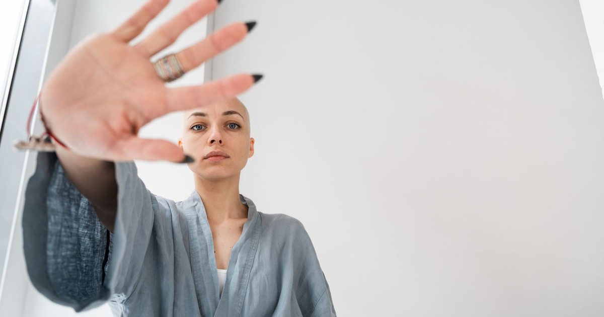 From below of young female in robe demonstrating control gesture while looking at camera in hospital on white background
