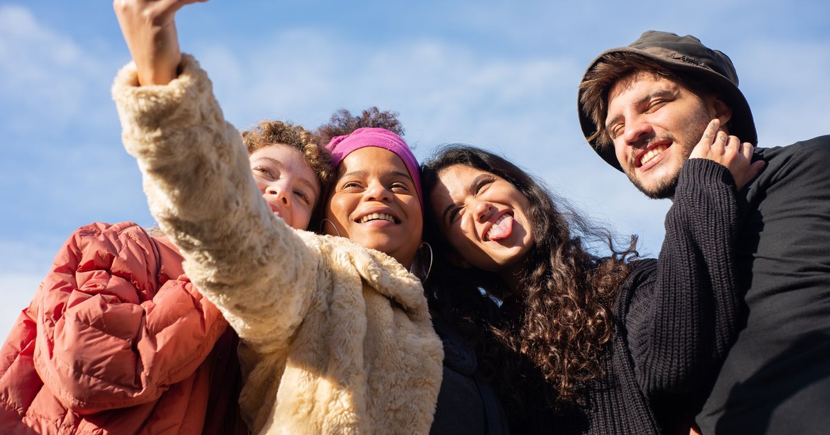 A joyful group of diverse friends taking a selfie outdoors on a sunny day.