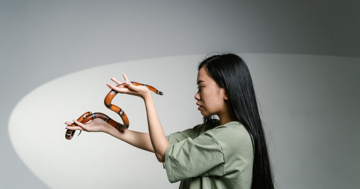 A woman confronting her fear by holding a snake, symbolizing overcoming anxiety.