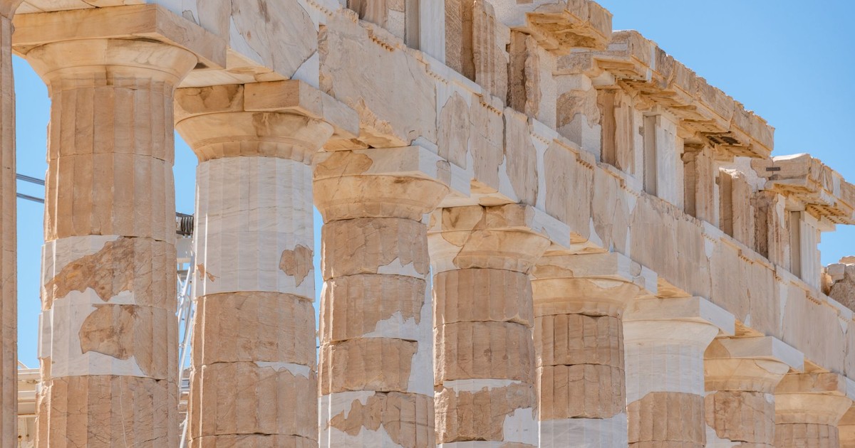 Close-up view of ancient marble columns of the Parthenon under clear blue sky in Athens.