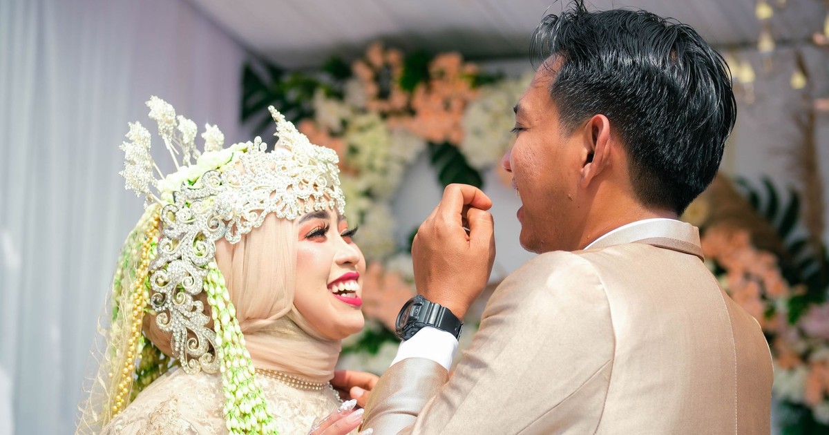 A joyful Indonesian couple shares a moment during their colorful wedding ceremony.
